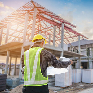An engineer looking at housing blueprints at a work site.