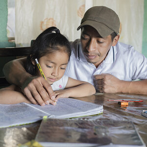 A young girl working on homework with her father.