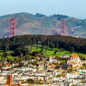 A red-painted bridge rises above the foothills surrounding a community - a photo of the Golden Gate Bridge. A red-painted bridge rises above the foothills surrounding a community - a photo of the Golden Gate Bridge.