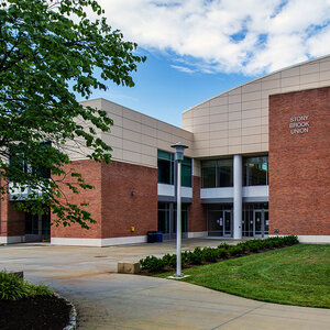 A modern college campus building surrounded by trees and a lawn – Stony Brook University.
