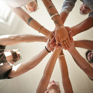 A group of people with their hands outstretched in a circle. A group of people with their hands outstretched in a circle.