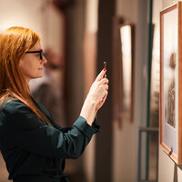 A woman taking a picture of an exhibit in a museum. A woman taking a picture of an exhibit in a museum.