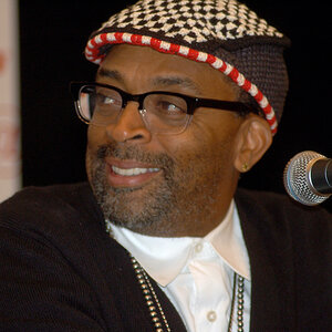 An African American man, wearing a cap and glasses, smiles and looks to his right - a photo of Spike Lee.
