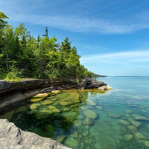 The clear waters of Lake Superior reveal large rocks and stones underwater.