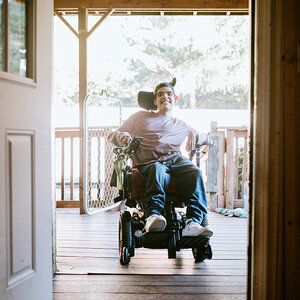 A man entering his home in a wheelchair. A man entering his home in a wheelchair.