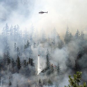 Firefighters battling wildfires from helicopters. Firefighters battling wildfires from helicopters.