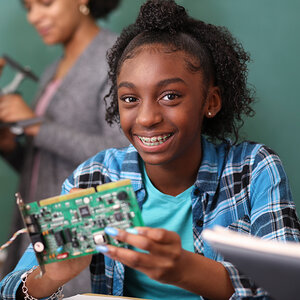 A smiling teenage girl is working on a computer motherboard. A smiling teenage girl is working on a computer motherboard.