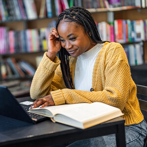 An female African American college student is studying in the library. An female African American college student is studying in the library.