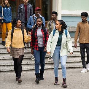 College students walk down a short flight of stairs outside a building.