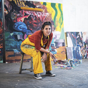 A painter in the studio surrounded by artwork.