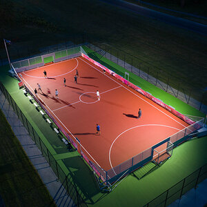 A mini-pitch soccer field, with youth playing at night, as seen from above.
