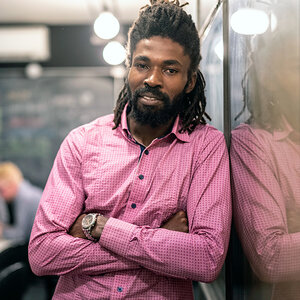 An African American business owner crosses his arms and poses for the camera.