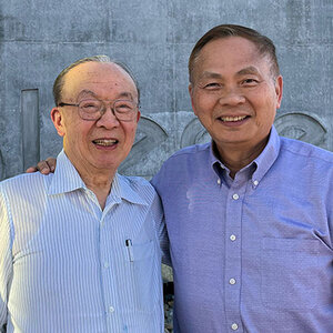 Two men standing shoulder to shoulder smiling for the camera.