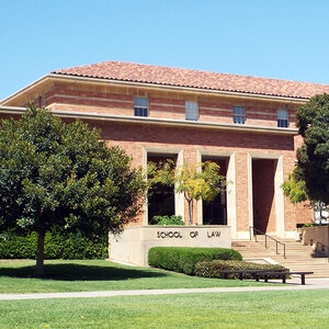 A college building with a terracotta roof surrounded by trees with a sign that reads: school of law.