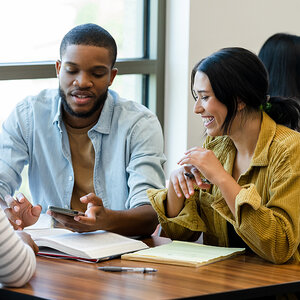 Two seated college students, male and female, work together on a project. Two seated college students, male and female, work together on a project.