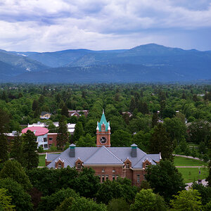 A college campus surrounded by trees with mountains rising in the background.