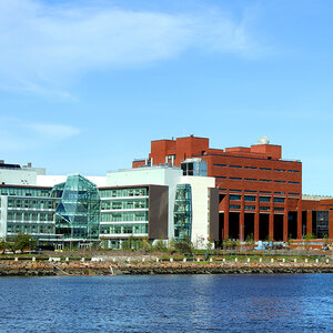 A view of modern college buildings along a waterfront boardwalk - UMass Boston.