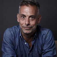 A headshot of a man with salt and pepper facial hair—a photo of Joe Mantello. A headshot of a man with salt and pepper facial hair—a photo of Joe Mantello.