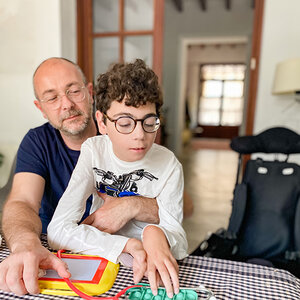 An autistic child sits with his father.