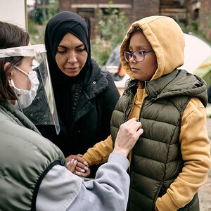 An aid worker examines a young Muslim girl in a refugee camp.