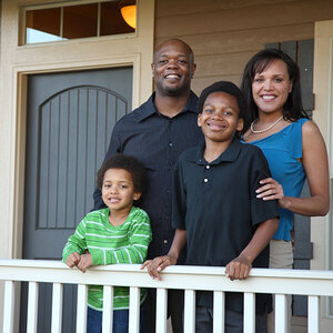 An African American family poses for a photo on the front porch of their home.
