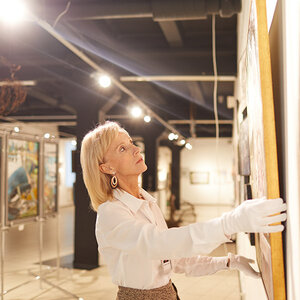 A woman installing art pieces in a museum. A woman installing art pieces in a museum.