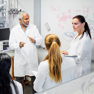 Scientists in lab coats discuss their findings. Scientists in lab coats discuss their findings.
