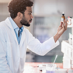 A pharmacist in a white jacket holds a medicinal bottle.