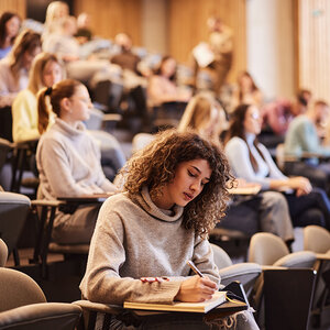 A woman taking notes in a college lecture. A woman taking notes in a college lecture.