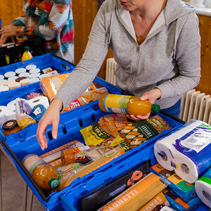 A volunteer at a food bank prepares a box of food for delivery. A volunteer at a food bank prepares a box of food for delivery.