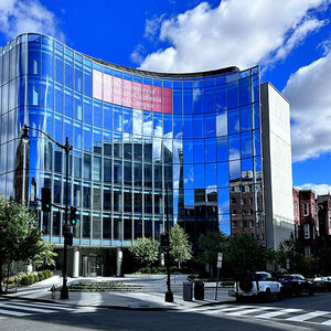 A modern office building with a deep blue sky reflecting off its curved glass façade. A modern office building with a deep blue sky reflecting off its curved glass façade.