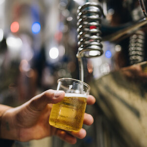 A hand holding a tasting glass filled with beer. A hand holding a tasting glass filled with beer.