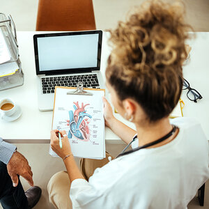 A doctor looking at a diagram of a heart. A doctor looking at a diagram of a heart.