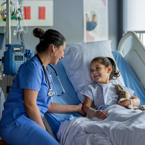 A child in a hospital bed smiling at her nurse. A child in a hospital bed smiling at her nurse.
