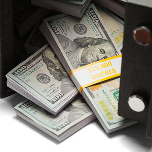 Neat stacks of one-hundred-dollar bills fall out of an open safe. Neat stacks of one-hundred-dollar bills fall out of an open safe.