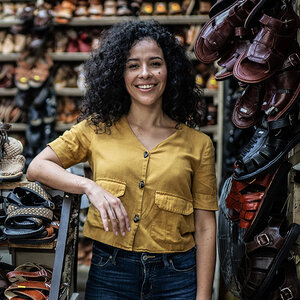 A female shoe store owner stands alongside racks of sandals. A female shoe store owner stands alongside racks of sandals.