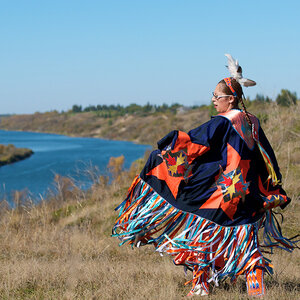 A Native American woman standing near a body of water.