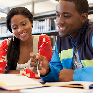 Two college students are studying at a table in a library.