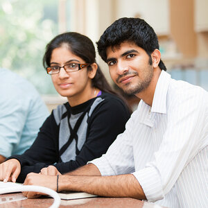 Indian students, a woman and a man, look at the camera, while studying. Indian students, a woman and a man, look at the camera, while studying.