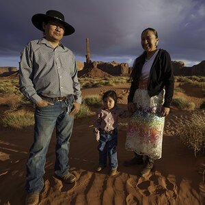 A Native American family stands in an area with mesas in the background A Native American family stands in an area with mesas in the background