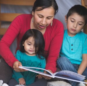 Native American mother reading to a boy and a girl.