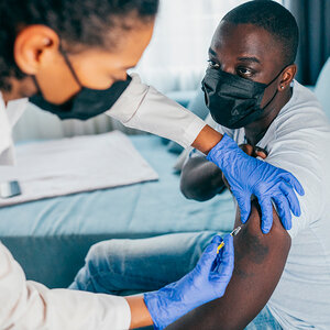 An African man receives an inoculation from a health worker. An African man receives an inoculation from a health worker.