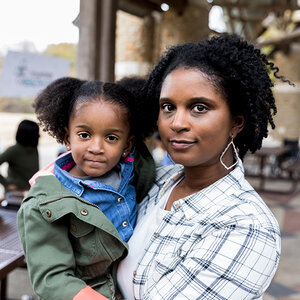 An African American mother holds her daughter as they look at the camera.